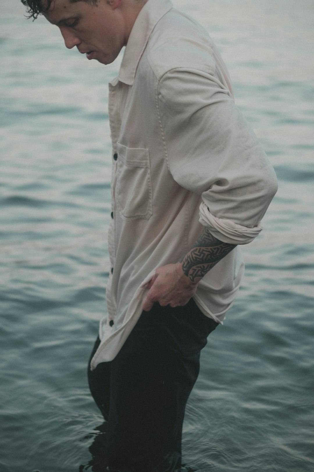 a-man-wearing-a-white-shirt-and-black-pants-with-a-tattoo-on-his-arm-vv-zq0fgrzc